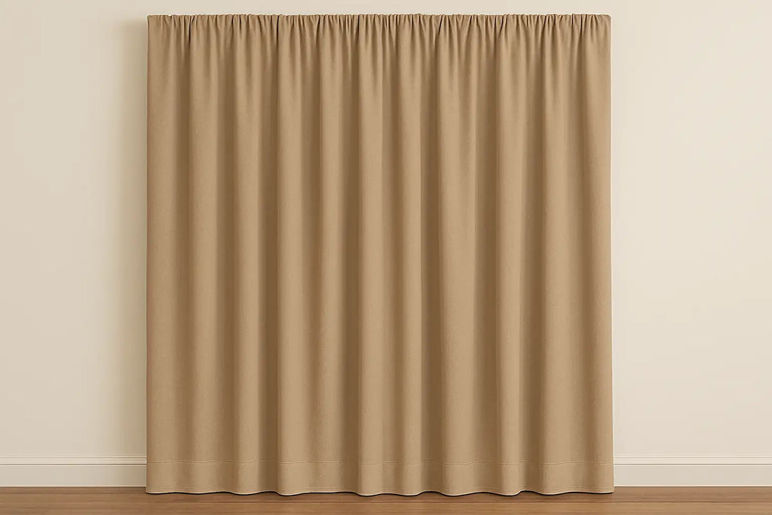 Solid beige curtains with neat pleats hanging against a light wall in a minimal living space